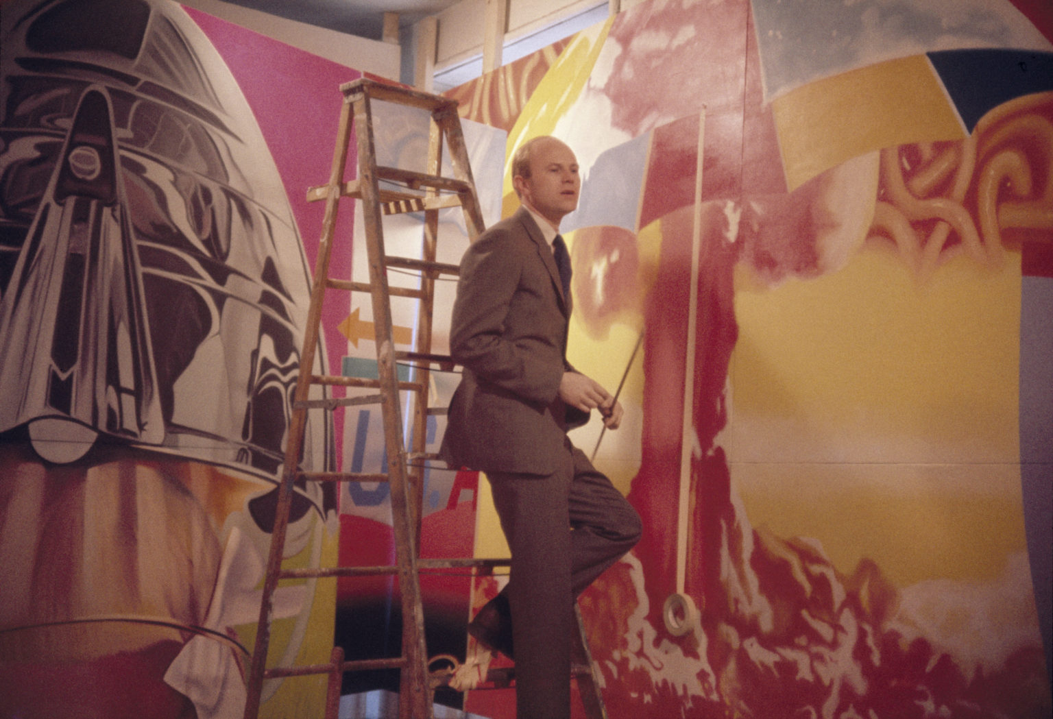 James Rosenquist standing on a ladder in front of F-111 in progress in his Broome Street studio